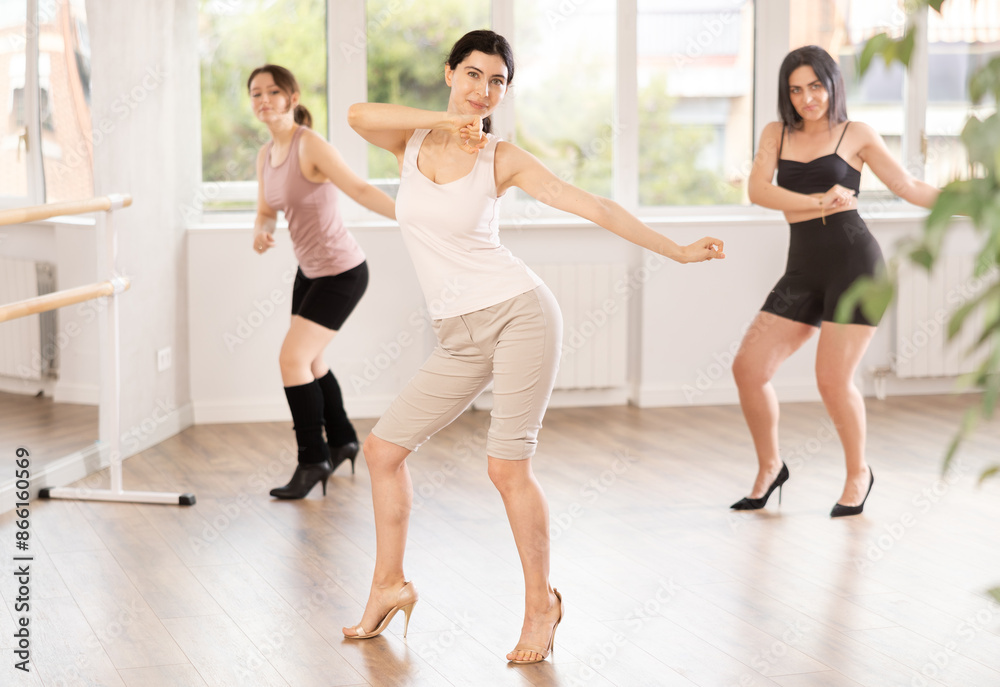 Obraz premium Group of girls dancing energetically in high heels in dance studio