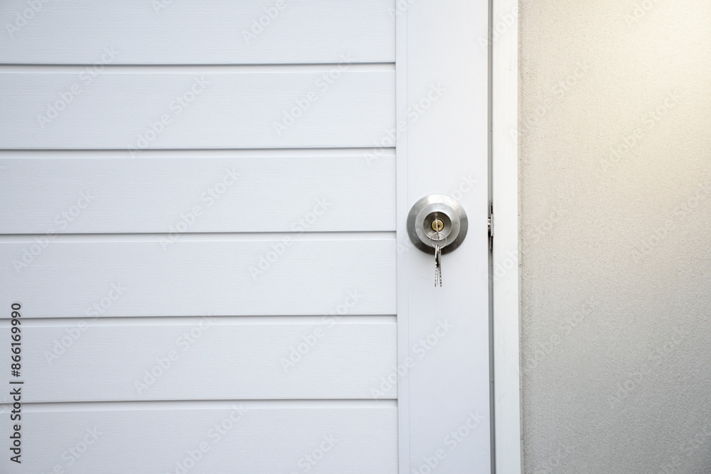 Silver knobs and keys on white modern wooden doors against the gray concrete background for forgot to close the door or lost the key and safety with security concept. Silver knobs and keys on white modern wooden doors against the gray concrete background for forgot to close the door or lost the key and safety with security concept.
