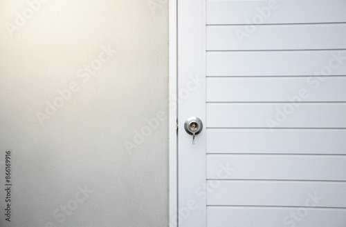 Silver knobs and keys on white wooden doors against the gray concrete background for forgot to close the door or lost the key and safety with security concept.