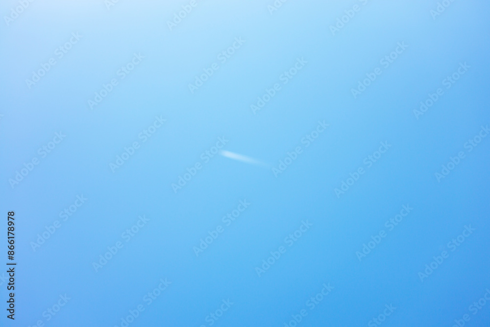 An airplane flies through the blue sky, leaving behind a white aircraft trail.This photo is suitable for making blue background material. An airplane flies through the blue sky, leaving behind a white aircraft trail.This photo is suitable for making blue background material.
