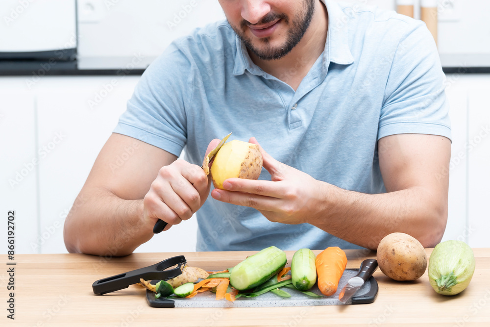 Fototapeta premium Close-up shot of a man peeling vegetables using special vegetable peelers in the kitchen 