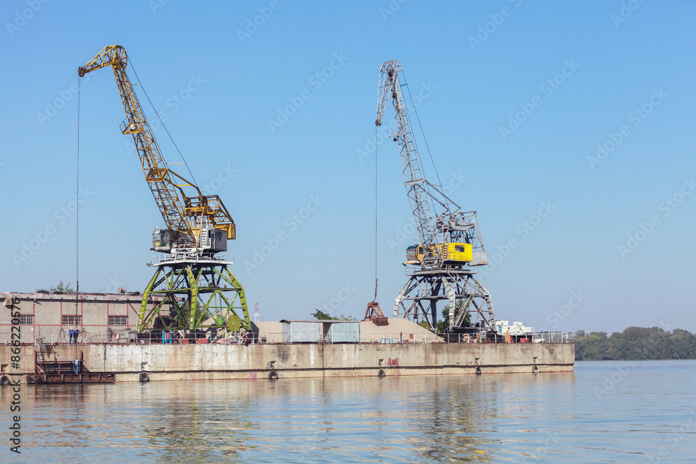 Yellow green portal cranes stand on a quay in harbor Yellow green portal cranes stand on a quay in harbor