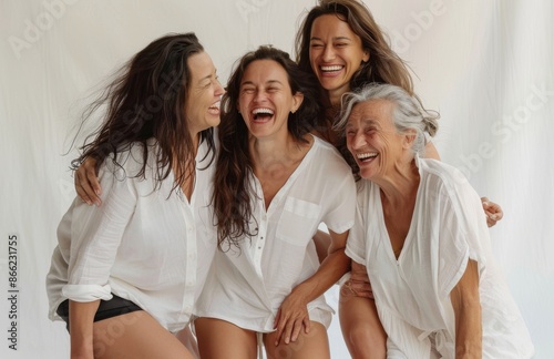 Four women of different ages laughing and bonding in casual white outfits photo