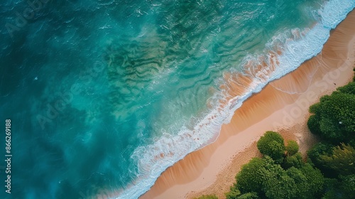 Aerial view of sandy beach with turquoise ocean waves crashing against the shore and lush green trees in the background. Tropical island paradise, summer vacation, travel destination, nature beauty.