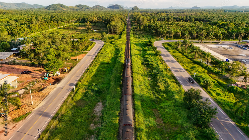 Naklejka premium aerial view Railway tracks in the suburbs. The railway line crosses the river. Train transportation. Railway tracks and road from above that is a long way Through natural areas in rural areas