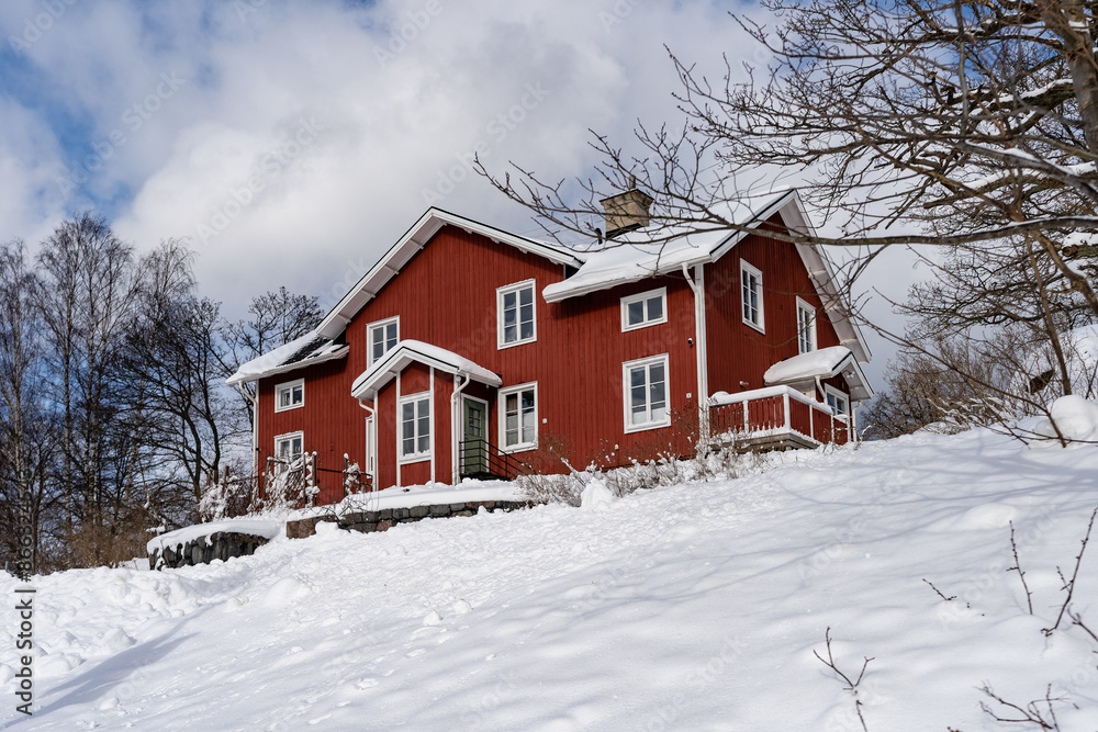Traditional old big red wooden house in winter countryside. Beautiful Swedish cottage or villa with big windows, terrace and balcony. Christmas landscape in northern Europe. Snowy village Traditional old big red wooden house in winter countryside. Beautiful Swedish cottage or villa with big windows, terrace and balcony. Christmas landscape in northern Europe. Snowy village