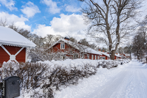 Traditional old big red wooden house in winter countryside. Beautiful Swedish cottage or villa . Christmas landscape in northern Europe. Snowy village. photo