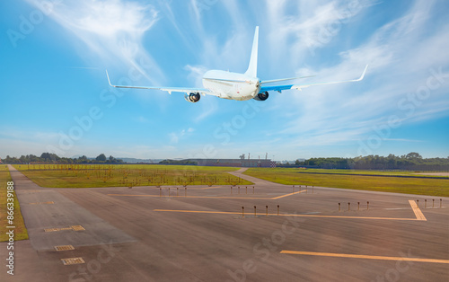 White Passenger plane fly up over take-off runway from airport runway lights in the background