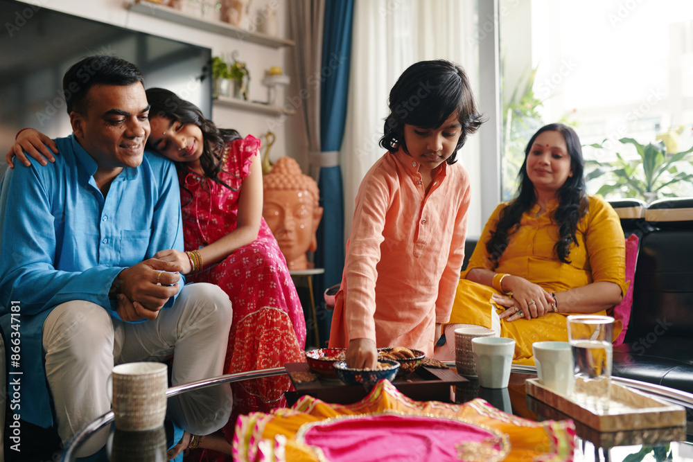 Obraz premium Indian family of four spending time together at home for cups of tea with dessert