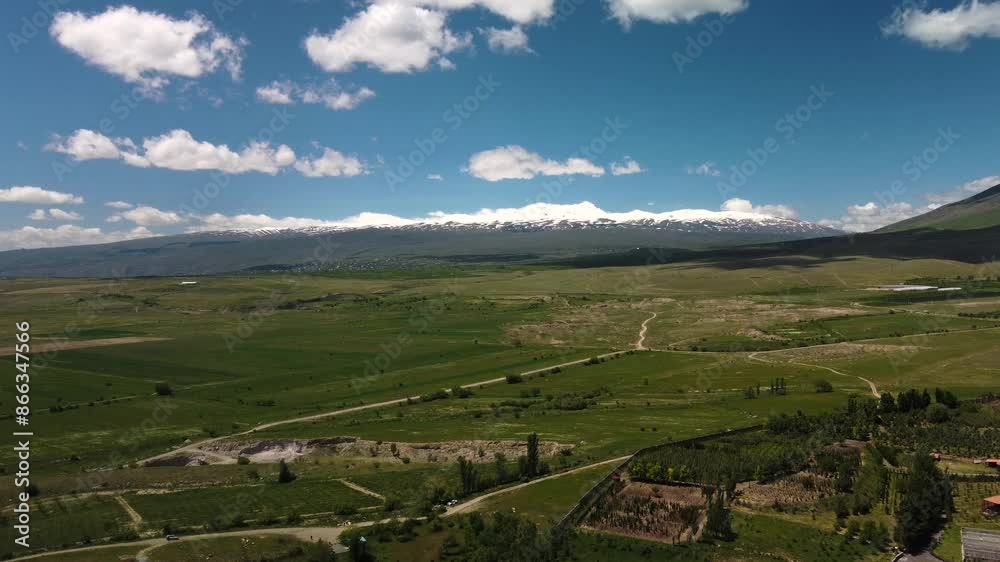 An Aerial View of a Verdant Landscape with Majestic Mountains in the Background An Aerial View of a Verdant Landscape with Majestic Mountains in the Background