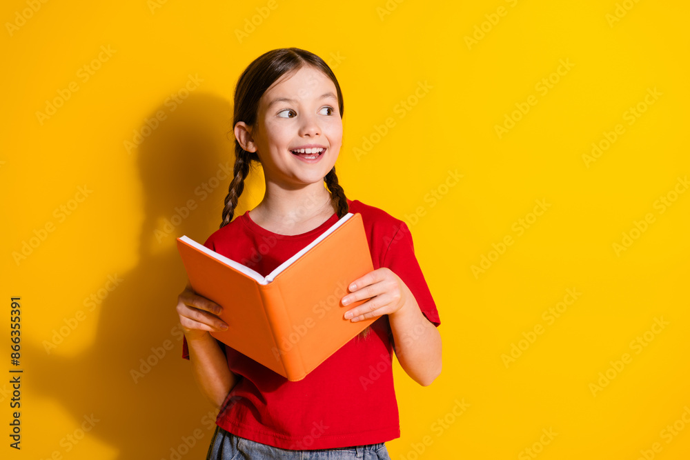 Photo of lovely small girl book look empty space wear t-shirt isolated on yellow color background Photo of lovely small girl book look empty space wear t-shirt isolated on yellow color background