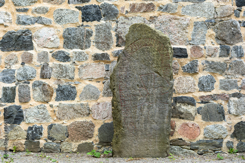 Traditional Rune stone. Old aged weathered granite gravestone in autumn. It was carved in 11th century. Ancient Big rock with runes patterns. Vikings Times. An old grave in the Sigtuna, Sweden.