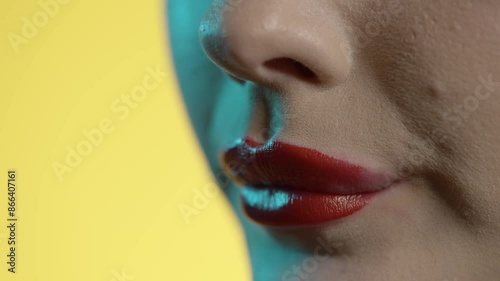 woman licking her lips, red lipstick, yellow background photo