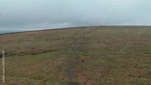 Wide angle view of tourist with orange backpack is trekking towards Five stones in England. Drone shot.  photo