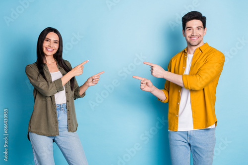 Photo of two nice young partners direct fingers empty space wear shirt isolated on blue color background