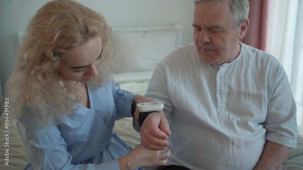 Daughter helps old father to measure blood pressure with home medical device blood pressure monitor. Health care in elderly age with family support. Daughter helps old father to measure blood pressure with home medical device blood pressure monitor. Health care in elderly age with family support.