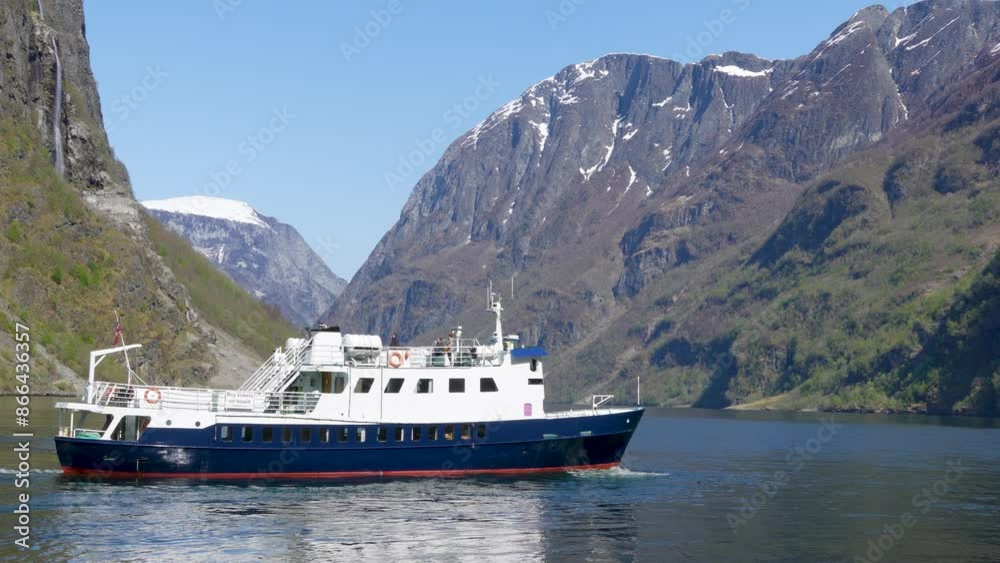 A cruise ship sails through the tranquil waters of the Sognefjorden flanked by towering cliffs. This is a World Heritage Site in Norway. A cruise ship sails through the tranquil waters of the Sognefjorden flanked by towering cliffs. This is a World Heritage Site in Norway.