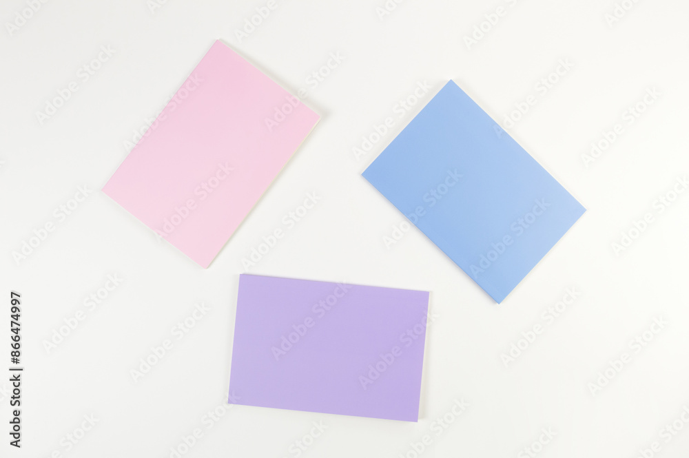 Top view of pink, purple and blue notebooks on white background. School, office wallpaper. Flat lay, copy space.