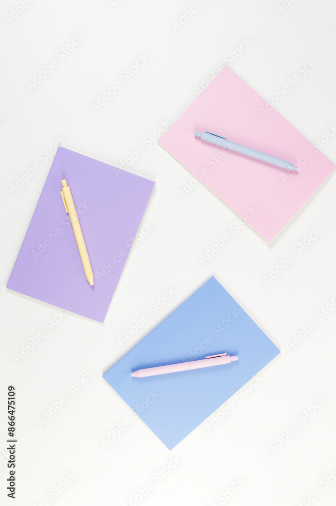 Top view of pink, purple and blue notebooks on white background. Pink, yellow and blue pens, school, office wallpaper. Flat lay, copy space. Top view of pink, purple and blue notebooks on white background. Pink, yellow and blue pens, school, office wallpaper. Flat lay, copy space.