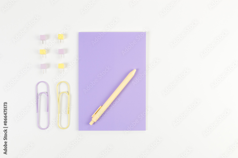Top view of purple notebook on white background. Paperclips, pen and pins. School, office wallpaper. Flat lay, copy space. Top view of purple notebook on white background. Paperclips, pen and pins. School, office wallpaper. Flat lay, copy space.
