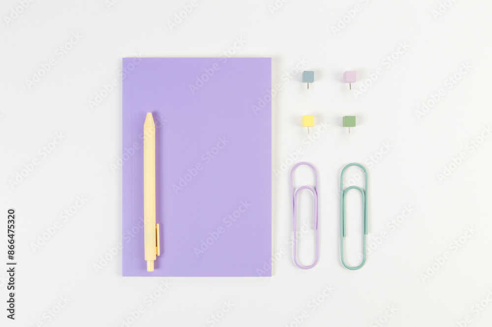 Top view of purple notebook on white background. Paperclips, pen and pins. School, office wallpaper. Flat lay, copy space. Top view of purple notebook on white background. Paperclips, pen and pins. School, office wallpaper. Flat lay, copy space.