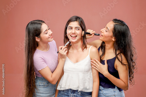 Two Glamorous Women Are Applying Makeup On One Woman While Standing