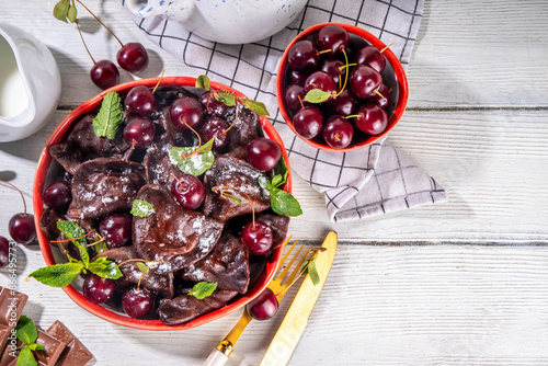 Sweet dessert chocolate dumplings vareniki with cherry berries and chocolate sauce, with sugar powder. Traditional ukrainian, polish, east european pierogi dumplings photo