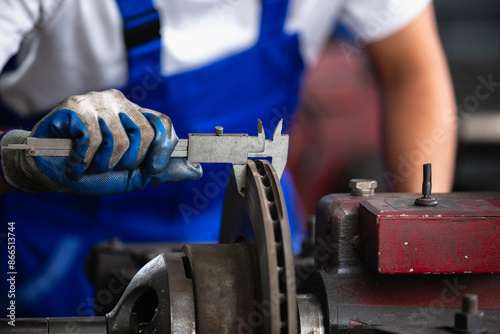 Tableau sur toile Engineering worker man wearing uniform safety working using vernier calipers measuring dimensions metal brake disc grinder in factory industrial, worker manufacturing industry concept
