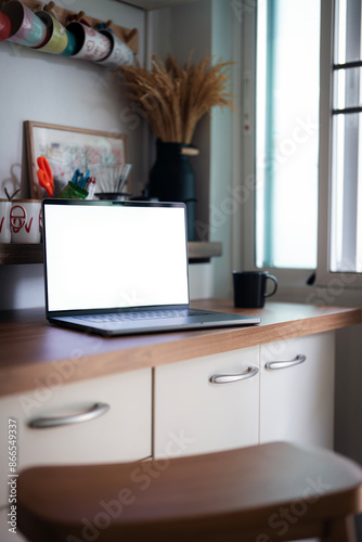 Open laptop with blank screen on a wooden desk in a kitchen room home office