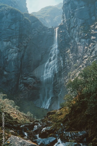 A waterfall is flowing down a rocky mountain © vefimov