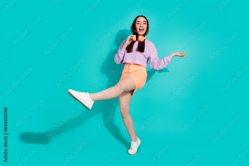 Full length photo of cheerful pretty lady dressed mini skirt dancing empty space isolated blue color background Full length photo of cheerful pretty lady dressed mini skirt dancing empty space isolated blue color background