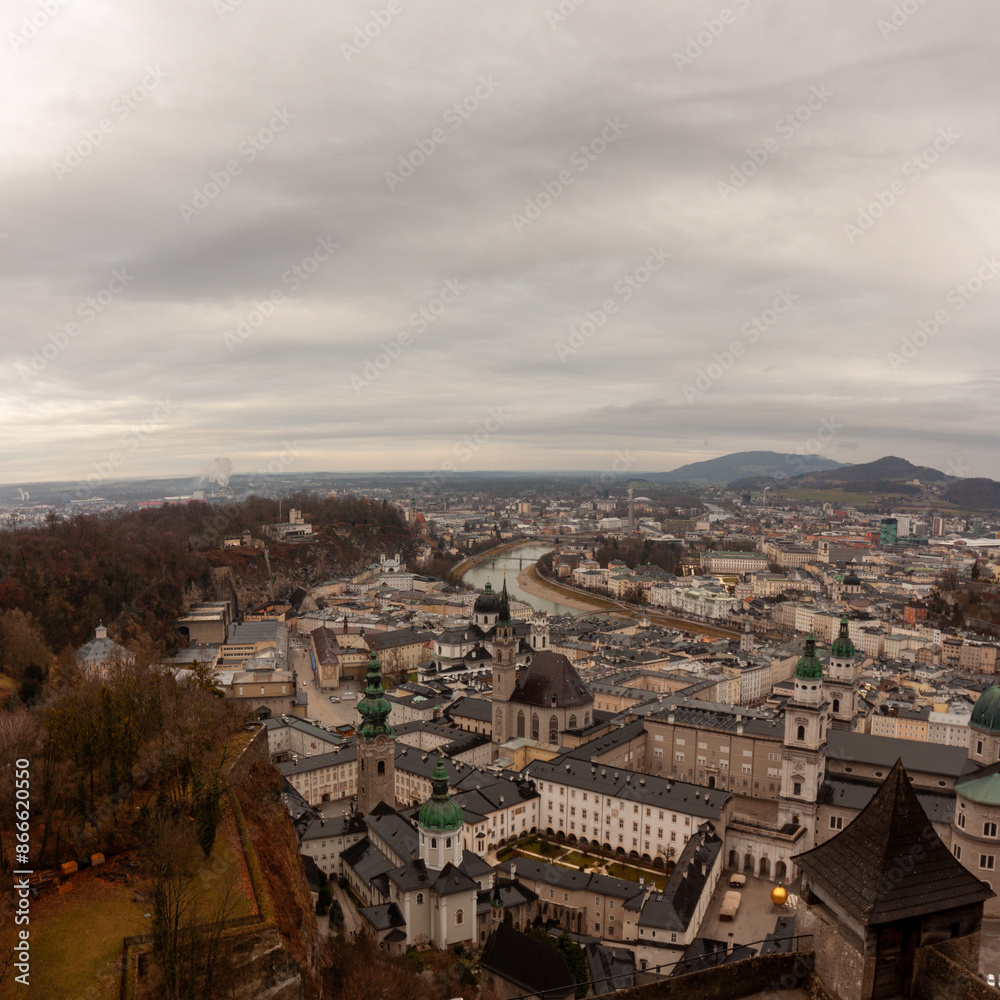 Obraz premium Panoramic view of the old town from the Hohensalzburg fortress. Cloudy and gloomy winter day, St. Peter's Abbey and Baroque Salzburg Cathedral