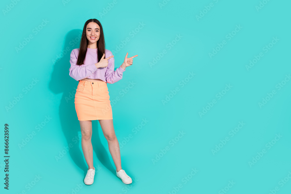Full size photo of attractive young woman point empty space dressed stylish violet clothes isolated on aquamarine color background Full size photo of attractive young woman point empty space dressed stylish violet clothes isolated on aquamarine color background