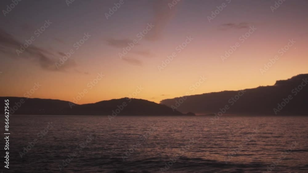 Sunset view from Cabo Estai capturing the distant silhouette of Monteferro. The serene seascape glows with hues of gold and pink, reflecting off the calm waters. Ideal for tranquil and scenic visuals. Sunset view from Cabo Estai capturing the distant silhouette of Monteferro. The serene seascape glows with hues of gold and pink, reflecting off the calm waters. Ideal for tranquil and scenic visuals.