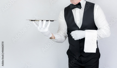 Classic Butler or Waiter in Black Waistcoat or Vest and Bowtie Holding Serving Tray. White Glove Service and Professional Hospitality.