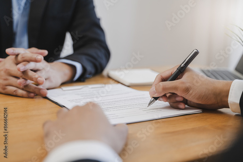 Fototapeta Naklejka Na Ścianę i Meble -  businessman sitting at desk holds pen signing contract paper, lease mortgage, employment hr or affirm partnership