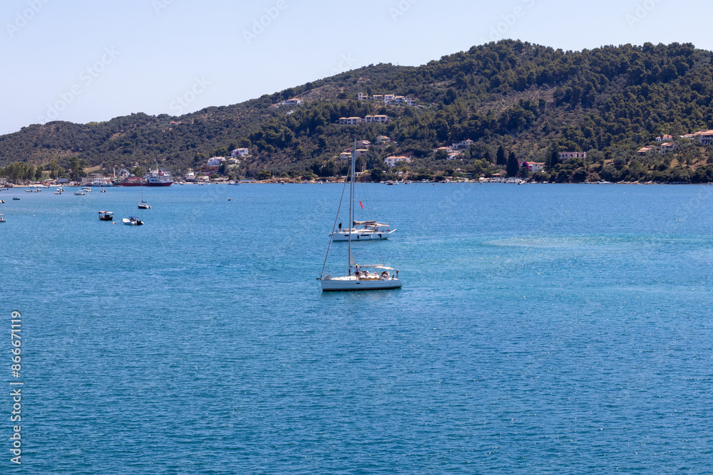 Skiathos, Greece A picturesque marina featuring boats docked by a tranquil coastal town, set against rolling hills under clear blue skies. Ideal for travel and tourism themes. Skiathos, Greece A picturesque marina featuring boats docked by a tranquil coastal town, set against rolling hills under clear blue skies. Ideal for travel and tourism themes.