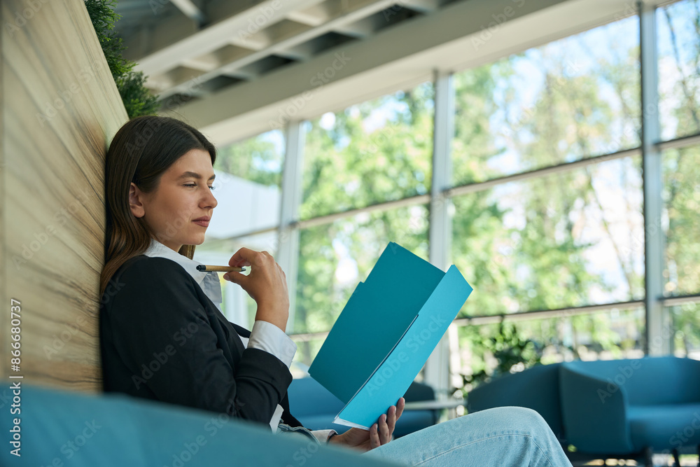 Caucasian woman reading documents in blue folder Caucasian woman reading documents in blue folder