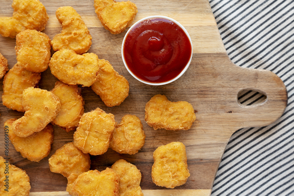 Naklejka premium Crunchy Chicken Nuggets with Ketchup on a wooden board, top view. Flat lay, overhead, from above.