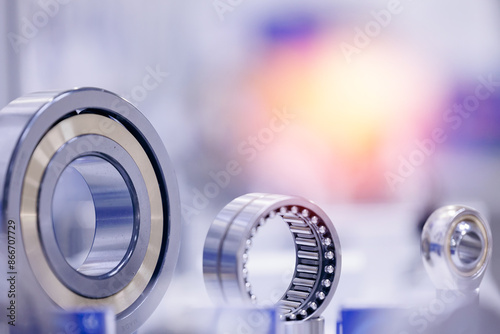 Set of chrome plated round deep roller ball and groove bearings on blur background. Products for heavy CNC equipment and mechanical engineering