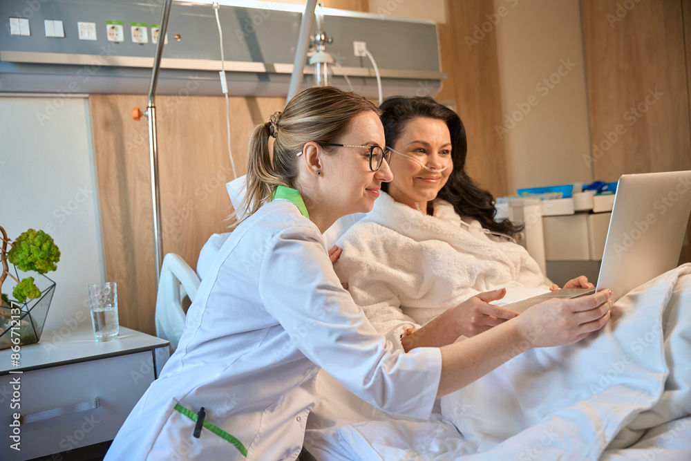 Obraz premium Brunette lady communicates online in a hospital room