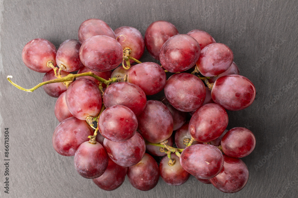 One juicy bunch of grapes on slate stone, macro, top view.