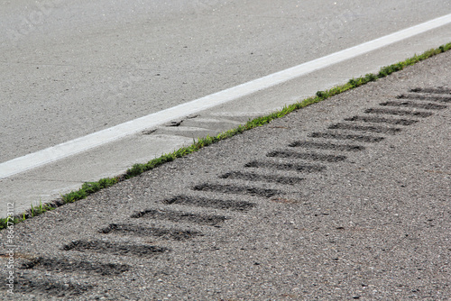 Safety rumble stripe and white markings on the gray road pavement or highway. Close up view of the texture on the surface.