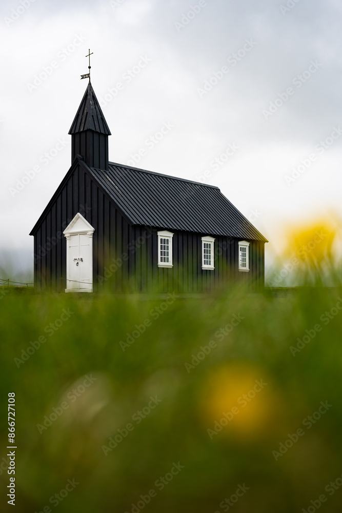 Stunning view of the black church of Budir with defocused grass in the foreground. Búðakirkja is a small wooden church located on the south side of Snæfellsnes, Iceland..