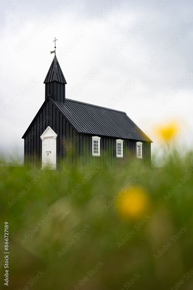 Stunning view of the black church of Budir with defocused grass in the foreground. Búðakirkja is a small wooden church located on the south side of Snæfellsnes, Iceland..