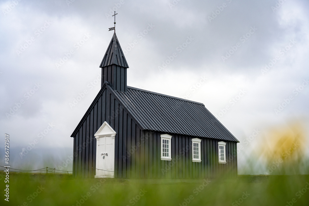 Stunning view of the black church of Budir with defocused grass in the foreground. Búðakirkja is a small wooden church located on the south side of Snæfellsnes, Iceland..