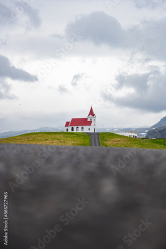 Obraz na płótnie Stunning view of the Ingjaldshólskirkja, a historic little red-roofed church located in Snæfellsnes penisula, A nice road leads down and back up a hill with great views of the mountains. w salonie