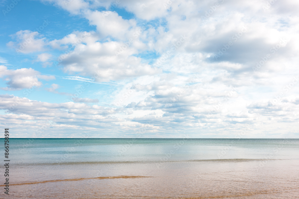 Fototapeta premium Partially cloudy, yet blue-sky day, moves over the calm wateers of Lake Michigan just off the beach at Harrington Beach State Park, Belgium, Wisconsin in early November