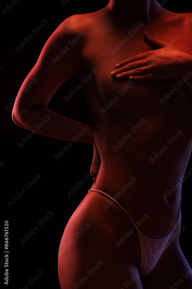 Naklejka premium Slim sexy woman in lingerie on a dark background. Her body is illuminated with blue and red lights.