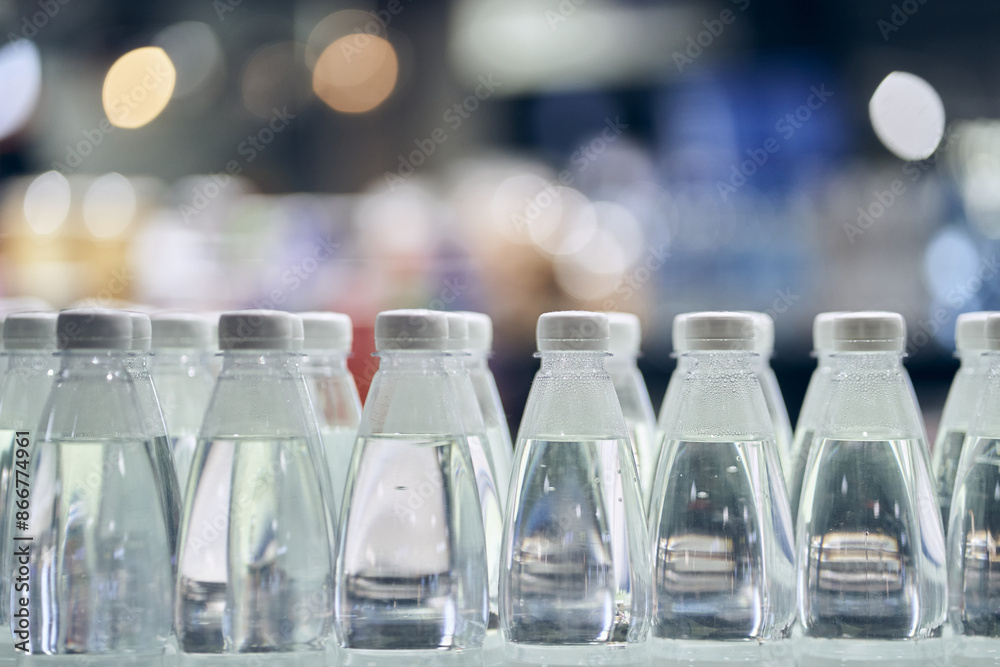 There are a lot of white caps from drinking water bottles and bottles with clean drinking water on a defocused background. With space to copy. High quality photo There are a lot of white caps from drinking water bottles and bottles with clean drinking water on a defocused background. With space to copy. High quality photo